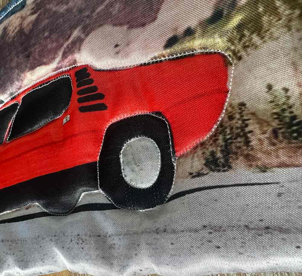 "Bil" är ett konstverk av Moa-Matilda Nilsson. Det är digitaltryck på polyester, med quiltning och broderi gjort 2025 i ett unikt exemplar och mäter 16 x 34 cm.